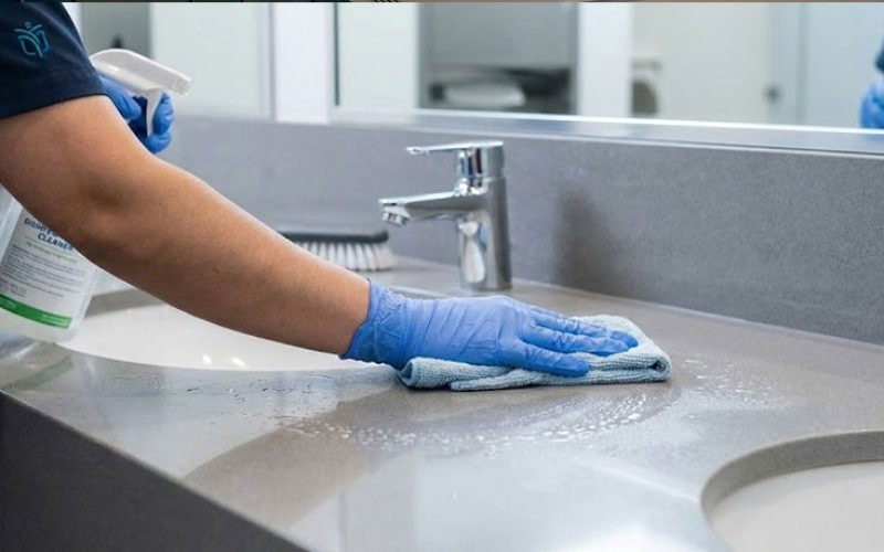 Professional commercial janitorial services staff sanitizing office bathroom counter top